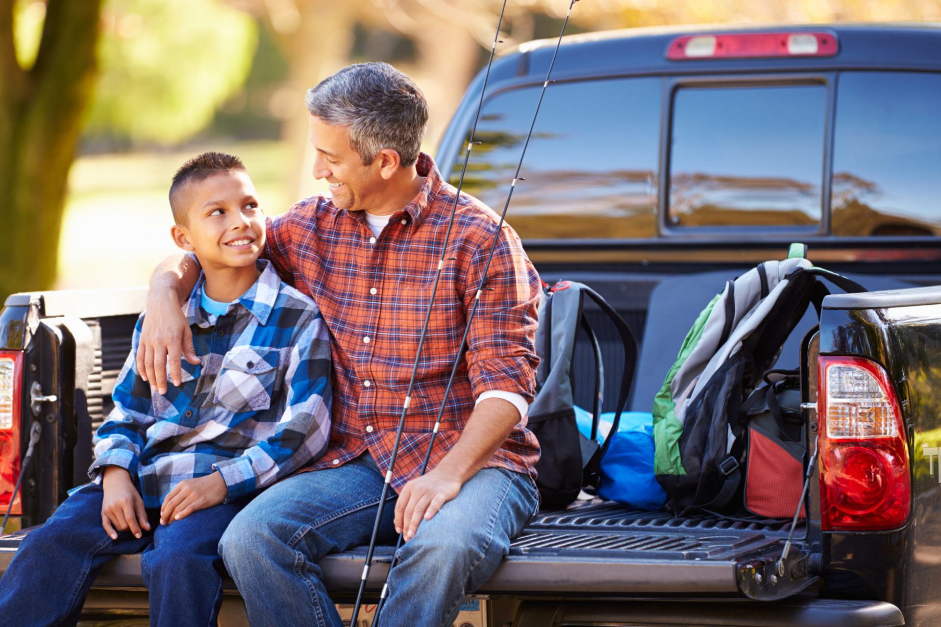 Father And Son Sitting In Pick Up Truck Camping Holiday