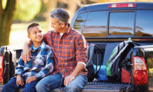 Father and son talking while sitting on the tailgate of a truck