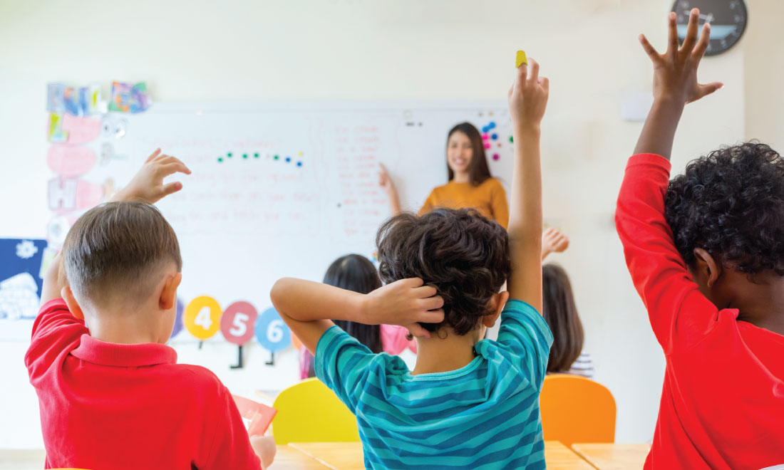 Kids in a class room raising their hands