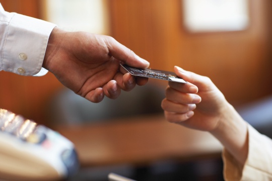 closeup photo of one hand passing a credit card to another hand