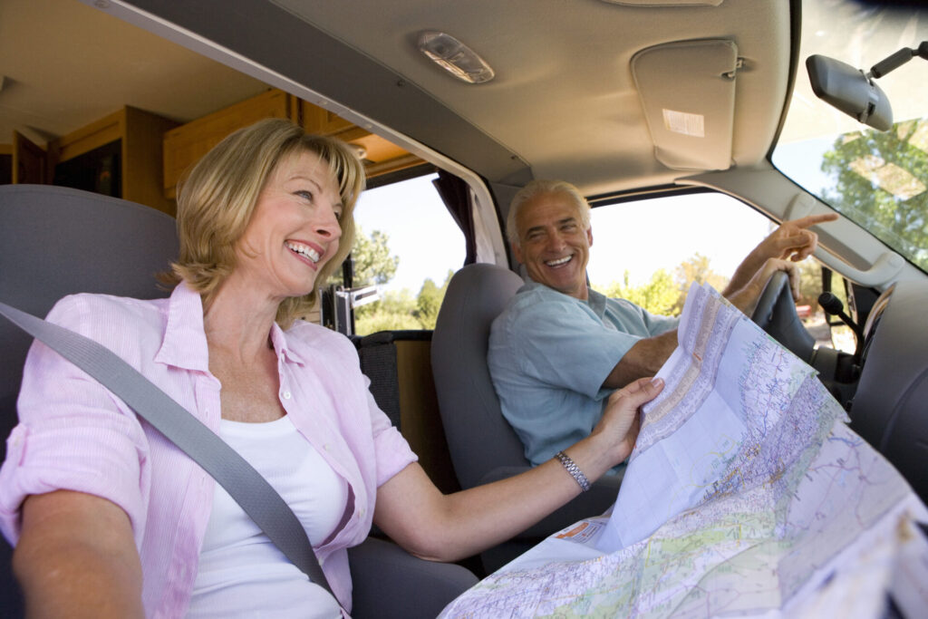 mature woman with map in motor home, next to husband, smiling, low angle view.