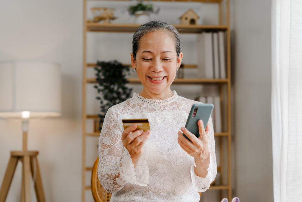 A woman smiles as she uses a smartphone to activate her new debit card.